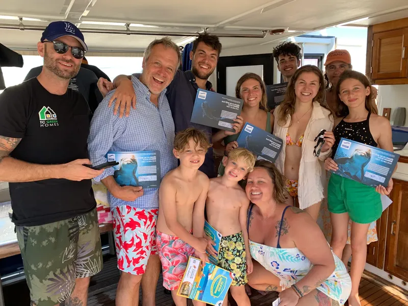 Groupe de personnes souriantes tenant des certificats de plongée sur un bateau