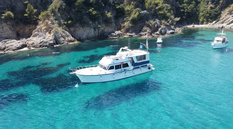 Bateau de plongée amarré dans une crique aux eaux turquoise claires