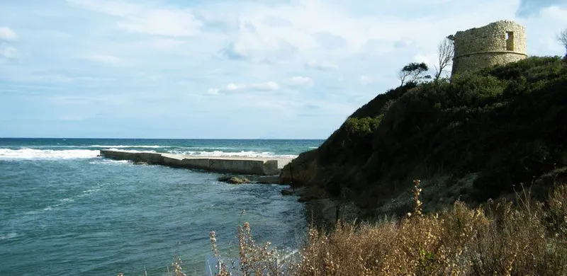 Côte rocheuse avec une tour en pierre et un quai en mer