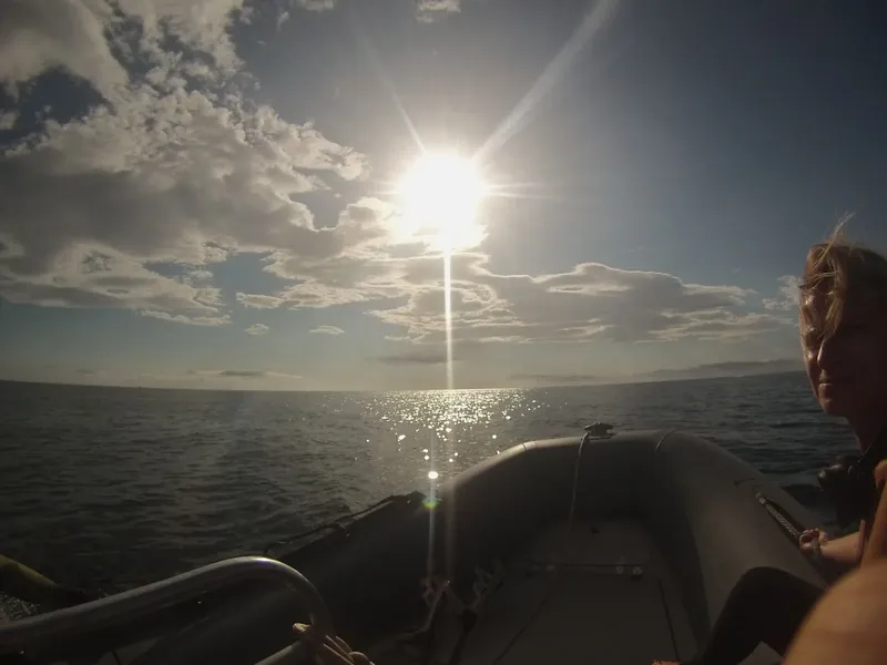 Personne à bord d'un bateau pneumatique, vue sur l'océan et le soleil
