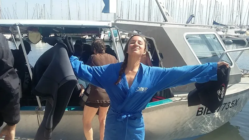 Une femme les bras ouverts sur un bateau de plongée ensoleillé