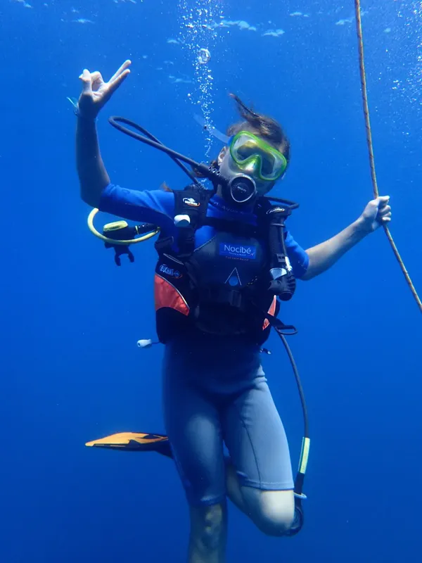 Plongeuse souriante faisant un signe de la main sous l'eau