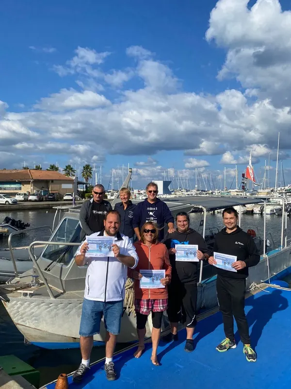 Groupe de plongeurs souriants posant avec leurs certificats sur un quai