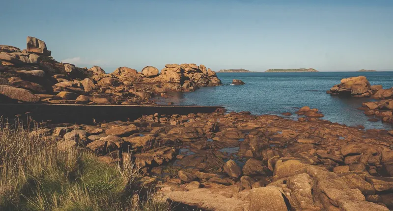 Côte rocheuse avec mer bleue et quelques îles au loin