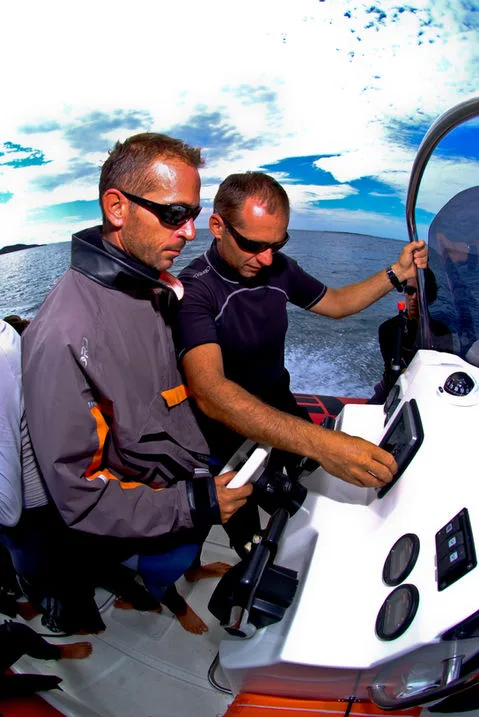 Deux hommes en tenue de plongée sur un bateau semi-rigide en mer