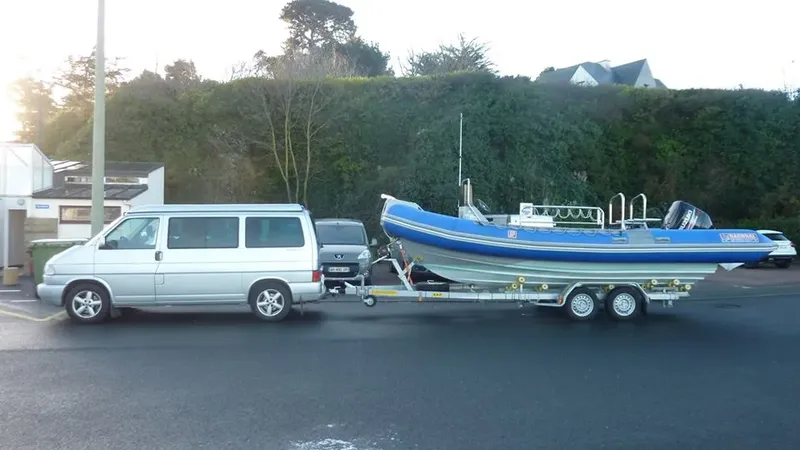 Bateau pneumatique bleu remorqué par un van sur un parking