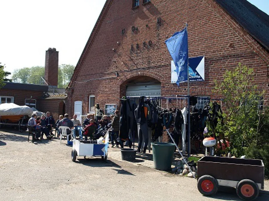 Groupe de personnes devant un bâtiment avec du matériel de plongée