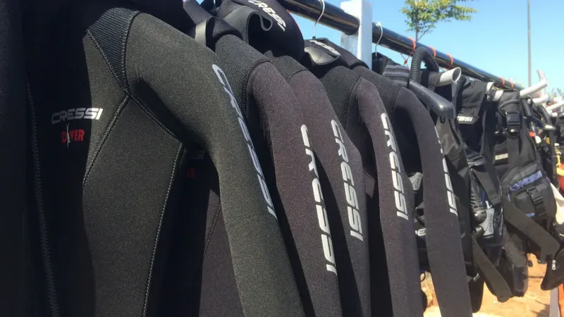 Rangée de combinaisons de plongée noires Cressi suspendues pour séchage