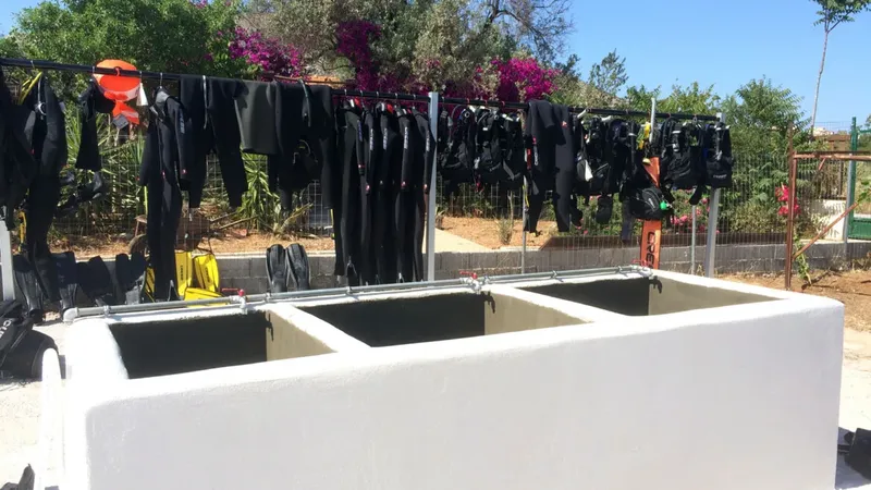 Bacs de rincage et combinaisons de plongée séchant au soleil