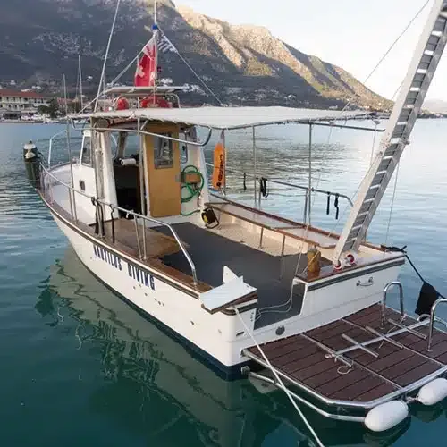 Bateau de plongée amarré dans une baie ensoleillée avec montagne