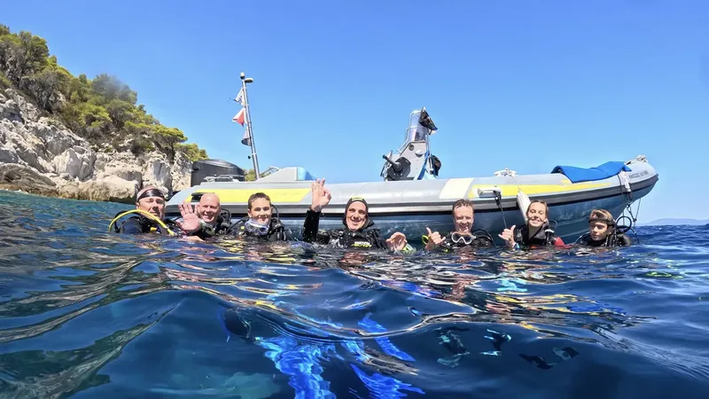 Plongée : groupe de personnes souriantes en combinaison près d'un bateau