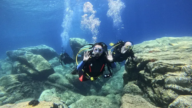 Deux plongeurs souriants font des signes de la main sous l'eau