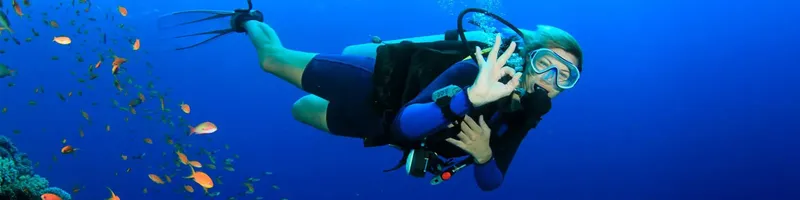 Plongeur souriant en pleine exploration sous-marine avec des poissons tropicaux
