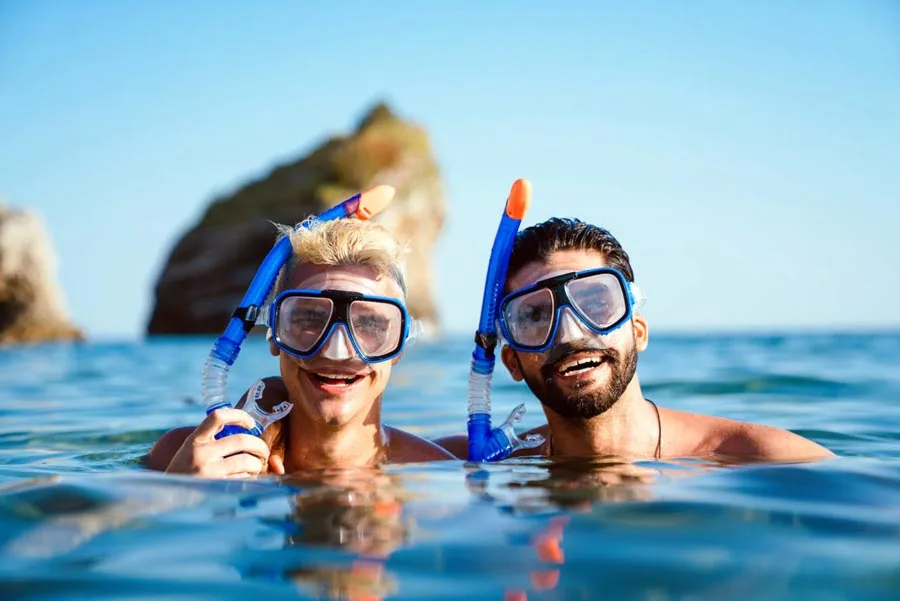 Deux hommes souriants avec masque et tuba dans l'eau claire