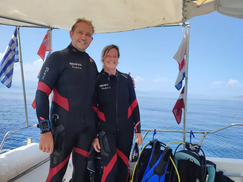 Deux plongeurs souriants en combinaison sur un bateau en mer