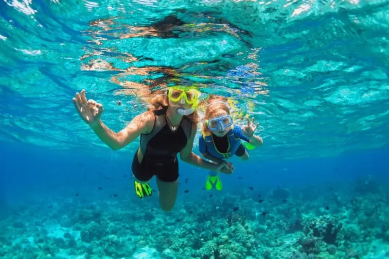 Deux personnes sourient et nagent avec masque et tuba en mer