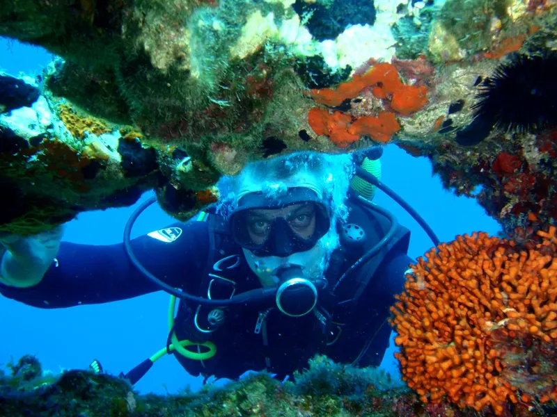 Plongeur souriant regardant la caméra dans un environnement rocheux coloré
