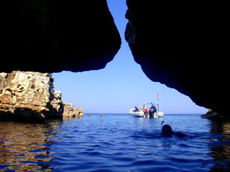 Plongeurs et bateau vus depuis l'intérieur d'une grotte sous-marine