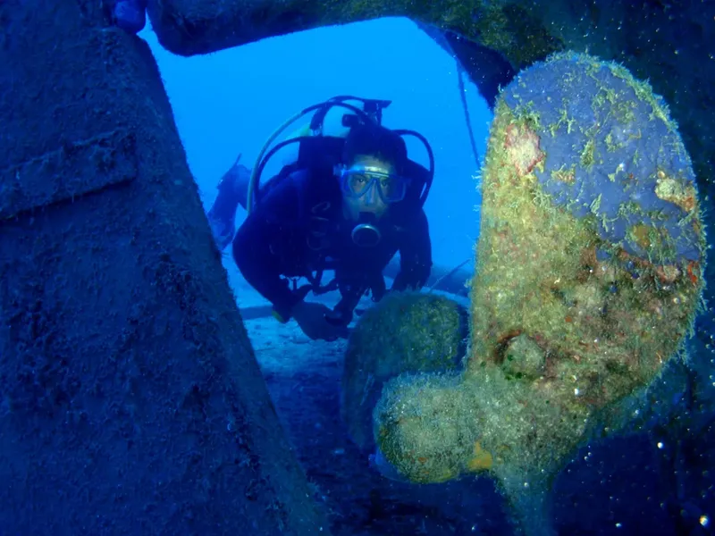 Plongeur explorant une épave sous-marine avec une visibilité claire