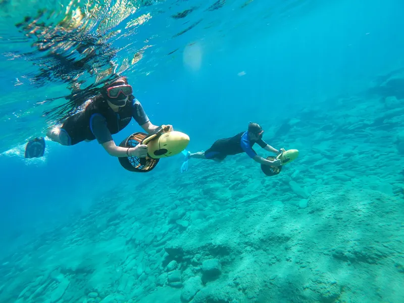 Deux plongeurs utilisent des scooters sous-marins au fond de l'eau