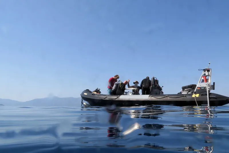 Plongeurs préparant leur matériel à bord d'un bateau pneumatique bleu