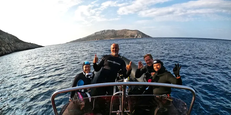 Groupe de plongeurs souriants sur un bateau en mer, paysage côtier