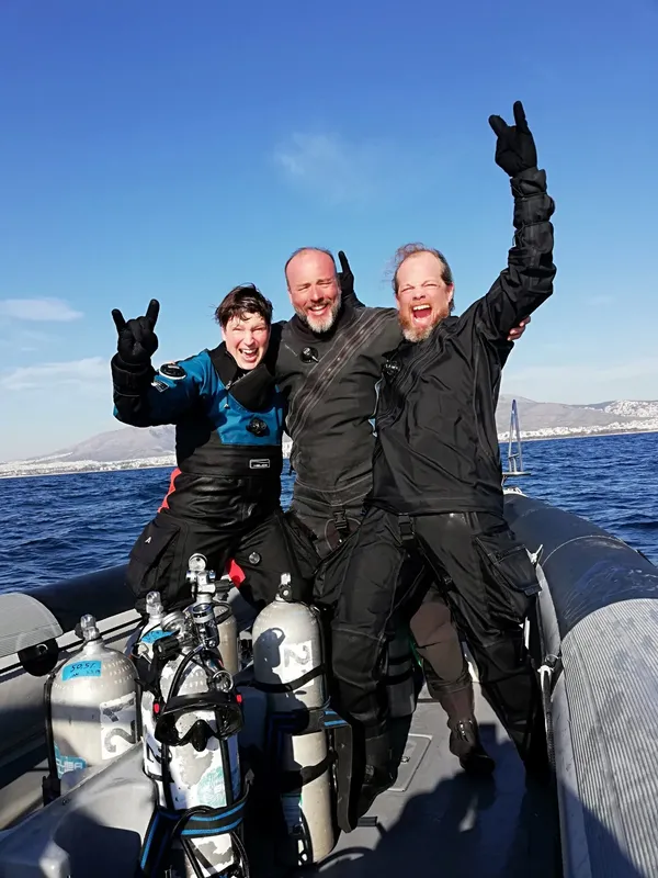 Trois plongeurs souriants sur un bateau pneumatique en mer