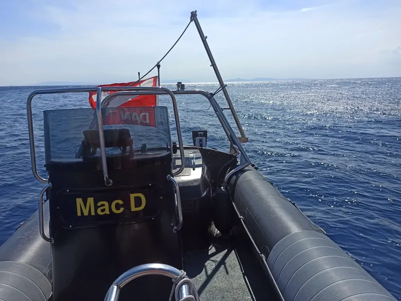 Bateau de plongée noir naviguant sur une mer bleue scintillante