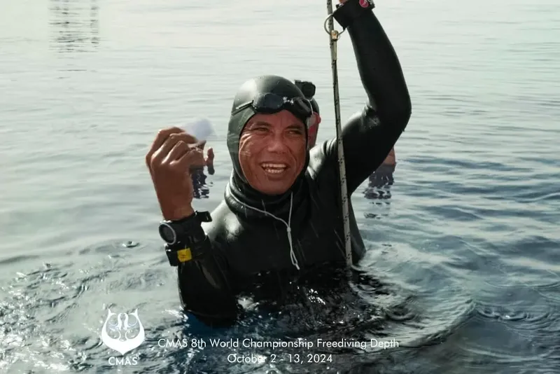 Apnéiste souriant émerge de l'eau avec une corde et des poids