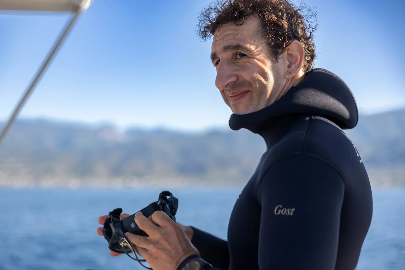 Plongeur souriant tenant un appareil photo sur un bateau en mer