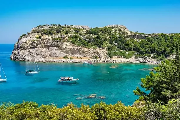 Cote rocheuse, mer turquoise, bateaux de plaisance et végétation luxuriante