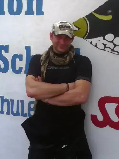 Un homme croise les bras devant un mur décoré d'une illustration