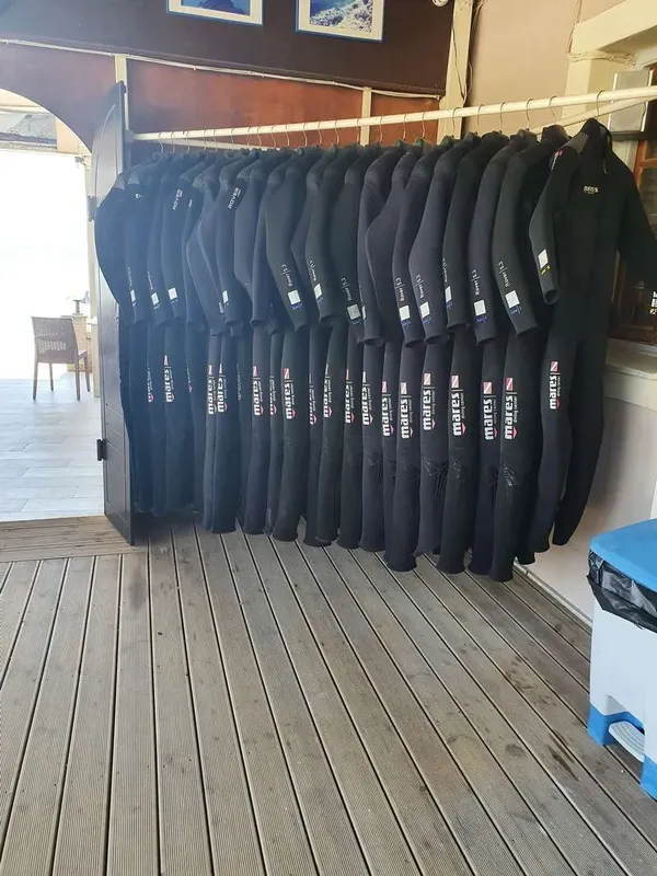 Rangée de combinaisons de plongée noires suspendues dans un local extérieur