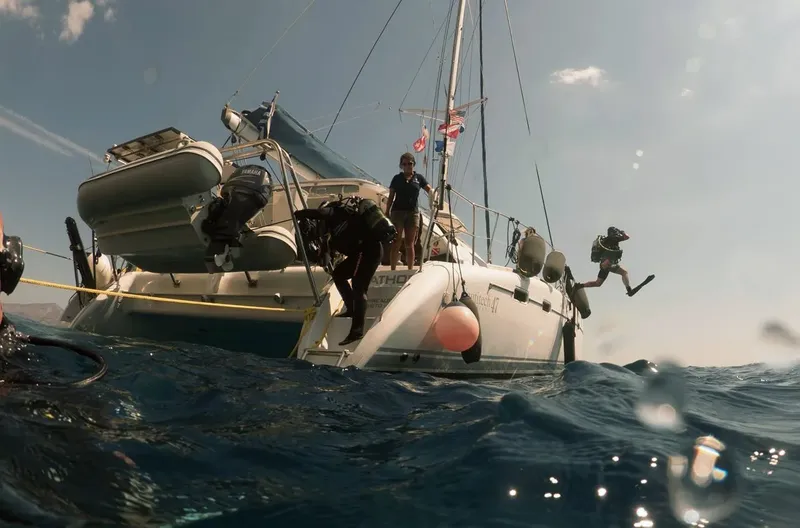 Plongeurs s'apprêtent à sauter d'un catamaran en mer, équipement visible