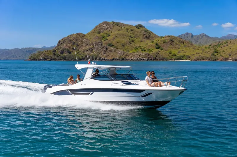 Bateau à moteur blanc avec des passagers naviguant sur une mer bleue