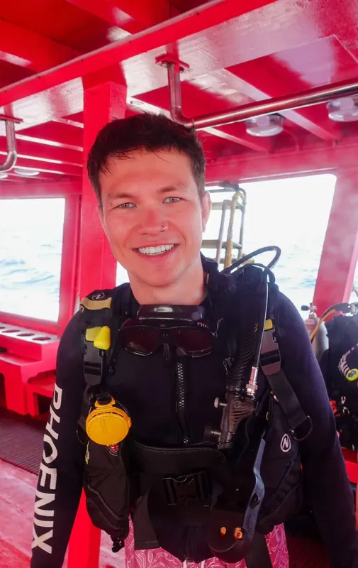 Plongeur souriant équipé à bord d'un bateau de plongée rouge