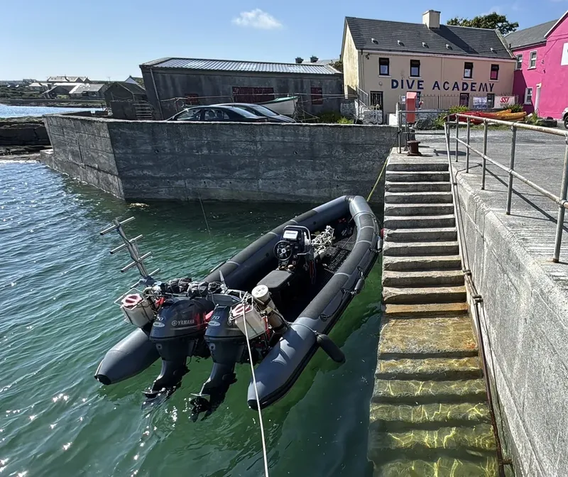 Bateau pneumatique amarré à un quai devant un bâtiment avec une enseigne