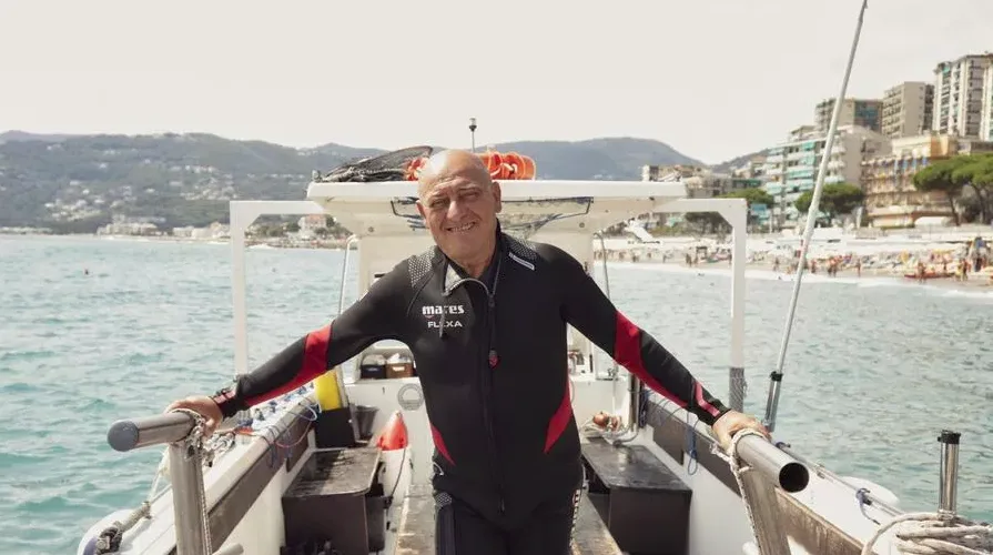 Homme en combinaison de plongée souriant sur un bateau en mer
