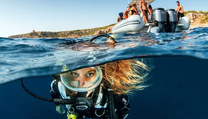 Plongeuse regardant la caméra, bateau de plongee et ciel bleu en arrière-plan