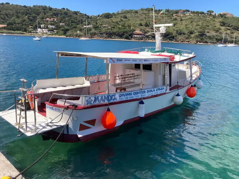 Bateau de plongée amarré dans une crique turquoise ensoleillée