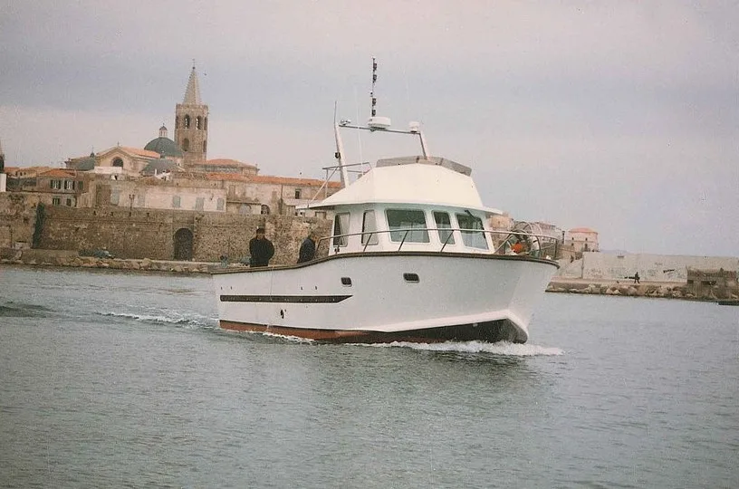 Bateau de plongée navigue près d'un port avec bâtiments anciens