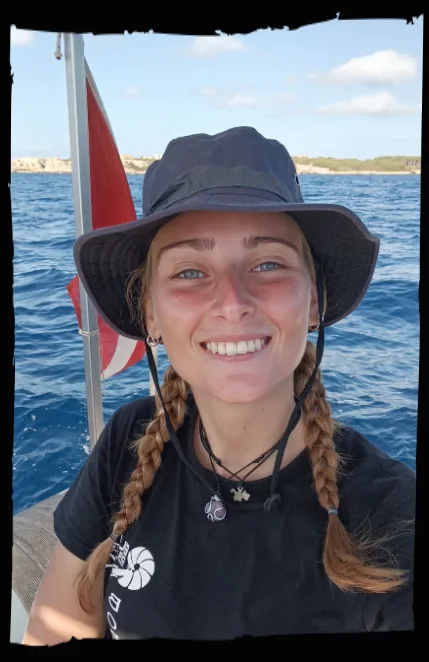 Jeune femme souriante portant un chapeau sur un bateau en mer