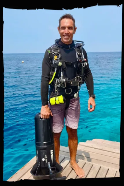 Plongeur souriant sur un ponton avec son équipement complet