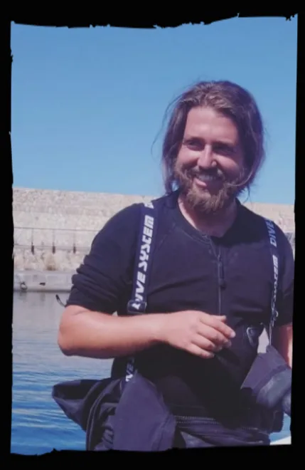 Un plongeur souriant, équipé d'un gilet, près de l'eau calme