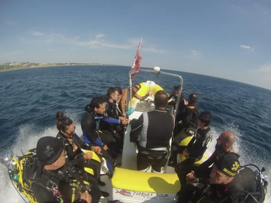 Groupe de plongeurs en combinaison sur un bateau semi-rigide jaune