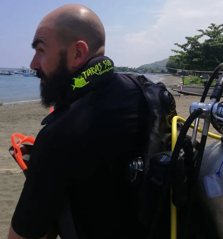 Plongeur équipé portant un gilet et une bouteille sur la plage