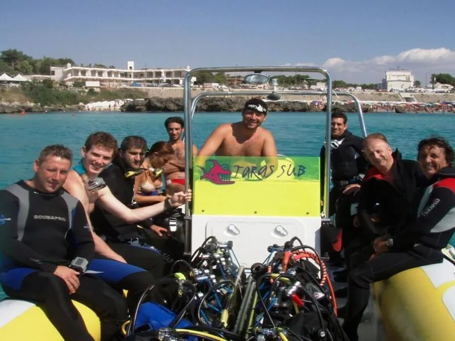 Groupe de plongeurs souriants à bord d'un bateau jaune et blanc