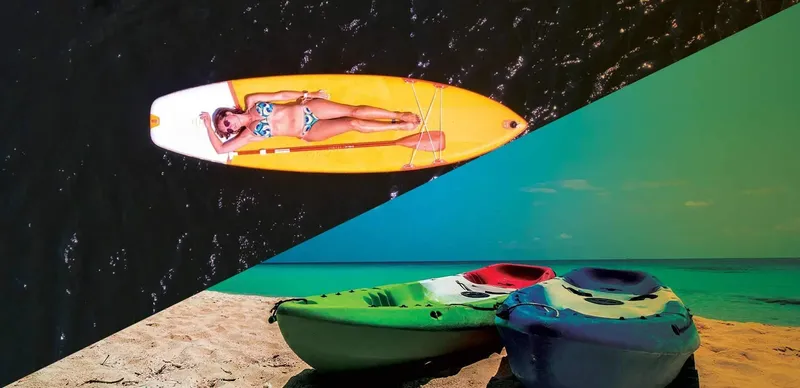 Femme sur planche de paddle et kayaks sur plage ensoleillée