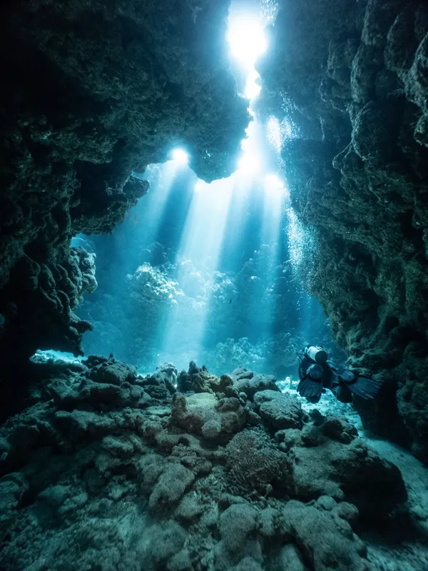 Plongeur explorant une grotte sous-marine éclairée par des rayons de soleil