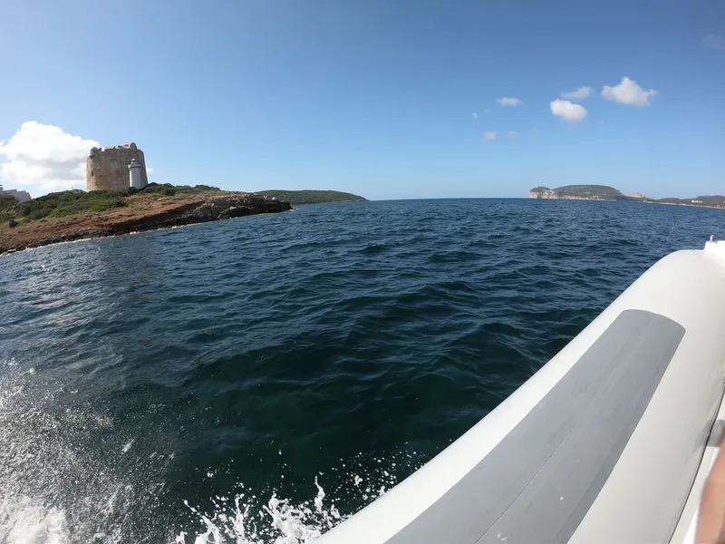 Bateau semi-rigide naviguant vers une tour genovese sur une île